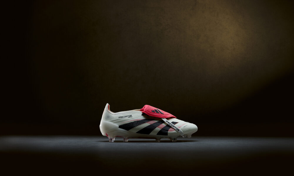 Side profile of the Adidas Predator boot showcasing red medial and lateral lines inspired by the 1998 Predator Accelerator